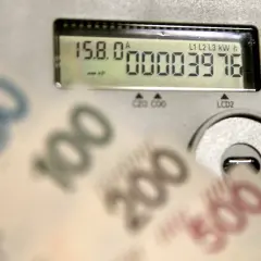 Liczniki energii PGE pokazują zużycie, a banknoty symbolizują opłatę sieciową.