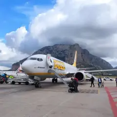 Samolot Buzz by Ryanair na lotnisku na Sycylii, z górami w tle.