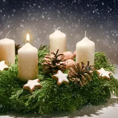 Ein Adventskranz mit vier Kerzen, Tannenzweigen, Zapfen und Sternen. Die erste Kerze brennt. Der Ursprung des Adventskranzes liegt im 19. Jahrhundert.