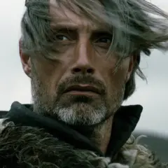Mads Mikkelsen mit Schwert und Pelzmantel, ein Bild, das an seine Rollen in Filmen und Serien erinnert.