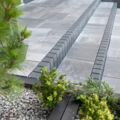 Nowe krawężniki w ogrodzie tworzą eleganckie schody. Zieleń iglaków i kamyczki dodają uroku.