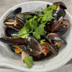 En skål med ångade musslor, garnerade med färsk koriander. Perfekt för ett enkelt musslor recept.