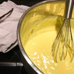 Crema pasticcera senza latte in preparazione, con bacca di vaniglia e frusta.