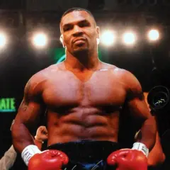 Mike Tyson's incredible build is on full display in the boxing ring, with red gloves ready.