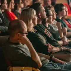 Widownia w teatrze siedząca w rzędach, skupiona na spektaklu.