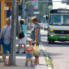 Ludzie czekający na autobus na przystanku, w tle autobus.