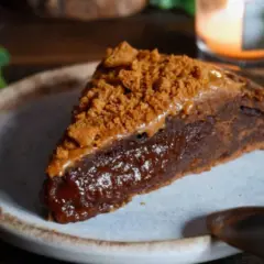 Une part de gâteau speculoos, riche et gourmande, garnie de miettes de biscuits et d'une sauce caramel.