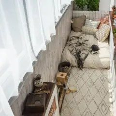 Wąski balkon w bloku inspiracje: przytulne miejsce do odpoczynku z materacem, kocem, poduszkami i roślinami.
