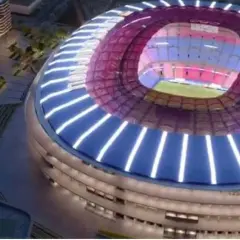 Nowe Camp Nou w nocnej odsłonie, z nowoczesną, oświetloną fasadą i dachem. Widać fragmenty otoczenia z budynkami i zielenią.