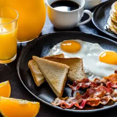Un délicieux petit déjeuner salé avec des œufs au plat, du bacon croustillant, des toasts et du jus d'orange frais.