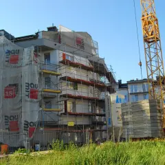 Budowa bloku mieszkalnego z żurawiem i rusztowaniami. Zastanawiasz się, ile deweloper zarabia na domu?