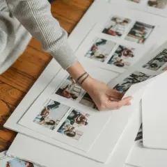 Dłoń przegląda wydrukowane zdjęcia z sesji, przygotowując fotoksiążkę.
