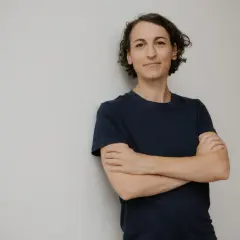 Frau mit verschränkten Armen, lächelnd, erinnert an Madame Moneypenny und ihren Denkfehler.