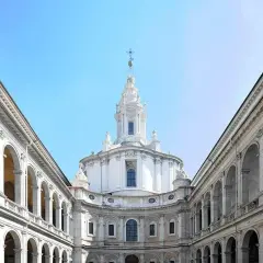 La chiesa della Sapienza a Roma, con la sua maestosa cupola e i portici ad arcate, incanta sotto un cielo azzurro.