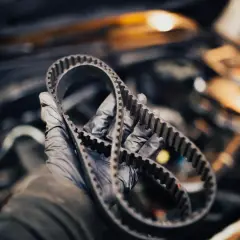 Rękawiczka mechanika trzyma pasek rozrządu. Sprawdź, jak sprawdzić czy rozrząd jest do wymiany, zanim dojdzie do awarii.