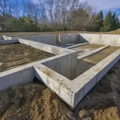 Fundament domu w budowie, z widocznymi różnymi rodzajami betonu, tworzy solidną podstawę dla przyszłego budynku.