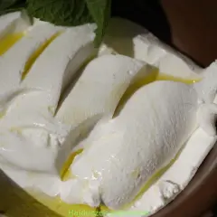 Kremowy ser labneh co to? Delikatny, biały ser z oliwą i miętą, podany w miseczce.