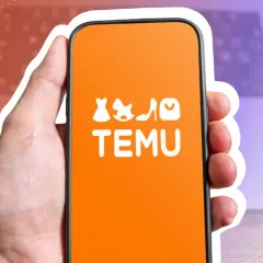 Hand hält Smartphone mit Temu-App. Die App zeigt Modeartikel und den Schriftzug "TEMU". Möglicherweise geht es um den Temu Zoll.