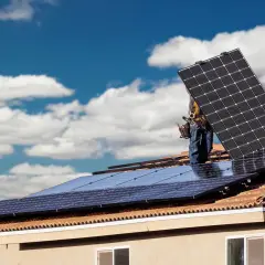 Instalatorzy montują panele słoneczne na dachu, przygotowując dom do systemu net billing.