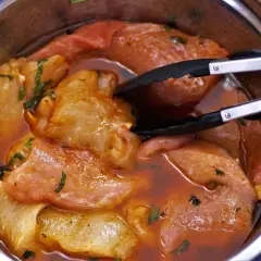 Morceaux de porc marinés dans une sauce rouge, prêts à être cuits. Une araignée de porc se cache dans la marinade.