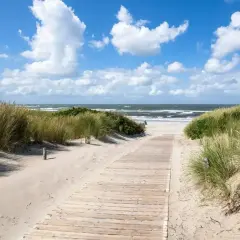 Ścieżka przez wydmy prowadzi na piaszczystą plażę. Idealne miejsce, gdzie na wakacje w sierpniu, z szumem fal i błękitem nieba.