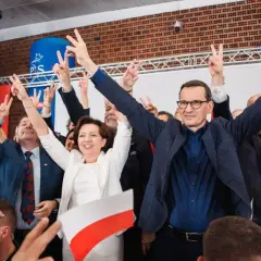 Radosny tłum z polskimi flagami i znakami zwycięstwa. W centrum Mateusz Morawiecki i inni politycy PiS, być może świętujący sukces, mimo że lista afer PiS jest długa.