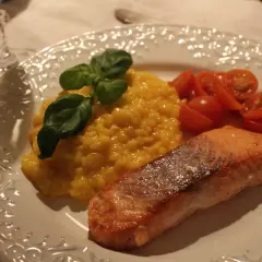 En härlig saffransrisotto med lax, garnerad med basilika och serverad med körsbärstomater. En festlig rätt!