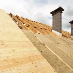 Struttura del tetto in legno con isolamento termico del tetto in lana minerale e due camini in costruzione.