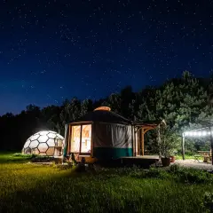 Nocne niebo pełne gwiazd nad jurtą i kopułą. Idealne klimatyczne miejsca na weekend we dwoje, z oświetlonym tarasem i grillem.