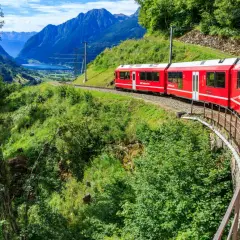 Czerwony pociąg jedzie przez malownicze szwajcarskie góry. Sprawdź swiss travel pass cena, by odkryć te widoki!