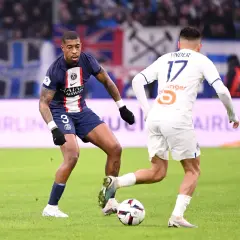 Kimpembe w ciemnym stroju PSG walczy o piłkę z zawodnikiem w białej koszulce.