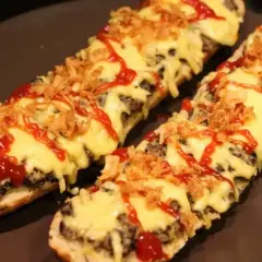 Dwie zapiekanki z airfryer na bagietce, z serem, chrupiącą cebulką i ketchupem.