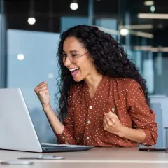 Excited woman celebrates fast Google Drive upload speed on her laptop.