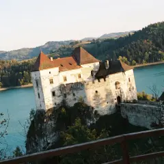 Niedzica-zamek trasa: malowniczy zamek na skale nad turkusową wodą, otoczony zielonymi wzgórzami.