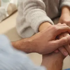 Dłoń mężczyzny obejmuje dłoń kobiety, pokazując, jak pocieszyć dziewczynę w trudnych chwilach.
