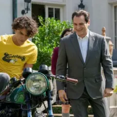 Un ragazzo su una moto e un uomo in giacca e cravatta sorridono. Le recensioni di "Your Honor" potrebbero descrivere questa scena.