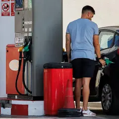 Hombre repostando su coche con gasolina 98. El surtidor muestra opciones de combustible, incluyendo la opción de alta octanaje.