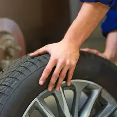 Mecánico revisa un neumático, pensando cuánto duran las ruedas de un coche.
