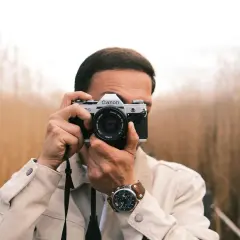 Man with a Canon AE-1, a classic choice for the best film camera for street photography, captures the moment amidst tall grasses.