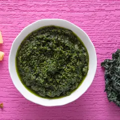 Pesto di cavolo nero crudo, ricco e vibrante, pronto per condire la pasta. Noci e mandorle completano gli ingredienti.
