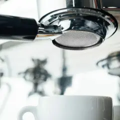 Filtr ekspresu DeLonghi, biała filiżanka i inne elementy. Zbyt częste odkamienianie ekspresu Delonghi może prowadzić do jego uszkodzenia.