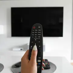 Dłoń trzymająca pilot do telewizora, gotowa do włączenia obrazu w rozdzielczości 4k.