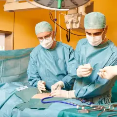 Chirurgen führen eine Hernien-OP mit Netz durch. Ein Team arbeitet konzentriert, um Komplikationen zu vermeiden.