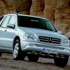Srebrny Mercedes ML 320 na tle skalistego krajobrazu.