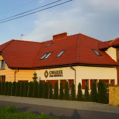 Dom Seniora Gwarek, nowoczesny budynek z czerwoną dachówką, otoczony zielenią.