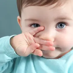 Niebieskooki maluch zasłania nosek rączką, sugerując brak apetytu u dziecka.