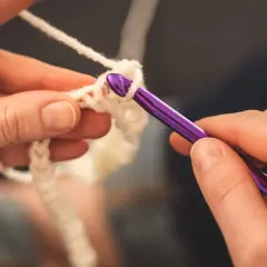 Ręce tworzą biały sznurek na szydełku. Zastanawiasz się, jakie szydełko do sznurka 3mm będzie najlepsze?