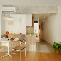 Stilvolle Einrichtung einer 45 qm Wohnung mit Esstisch, Küche und Blick ins Schlafzimmer. Helle Farben und Holzmöbel schaffen Gemütlichkeit.