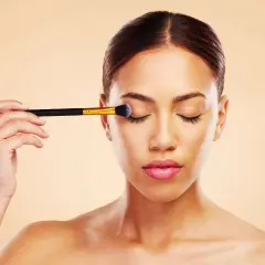 Donna applica ombretto con un pennello, un passo fondamentale per un make up perfetto.