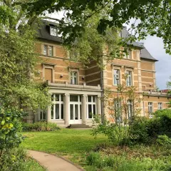 Prachtvolle Villa Zanders, umgeben von üppigem Grün, mit einem Weg, der sich durch den Garten schlängelt.